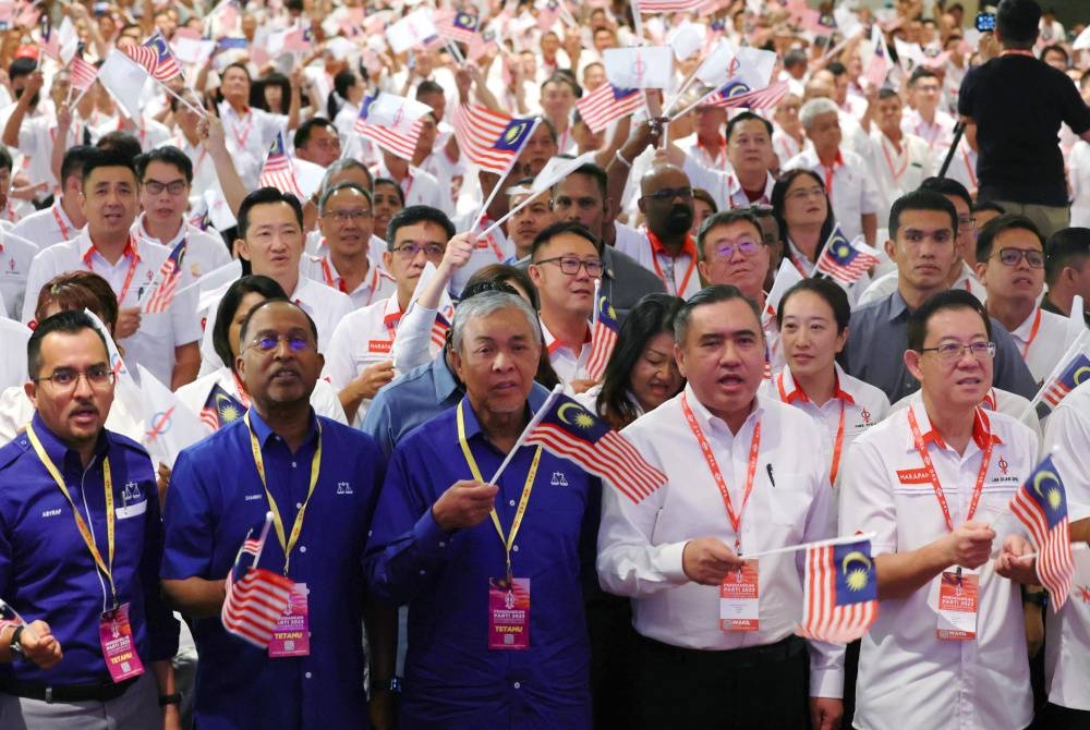 Ahmad Zahid (tengah) mengibarkan Jalur Gemilang ketika menyanyikan lagu 'Setia' pada Persidangan Parti DAP 2023 pada Ahad. - Foto Bernama