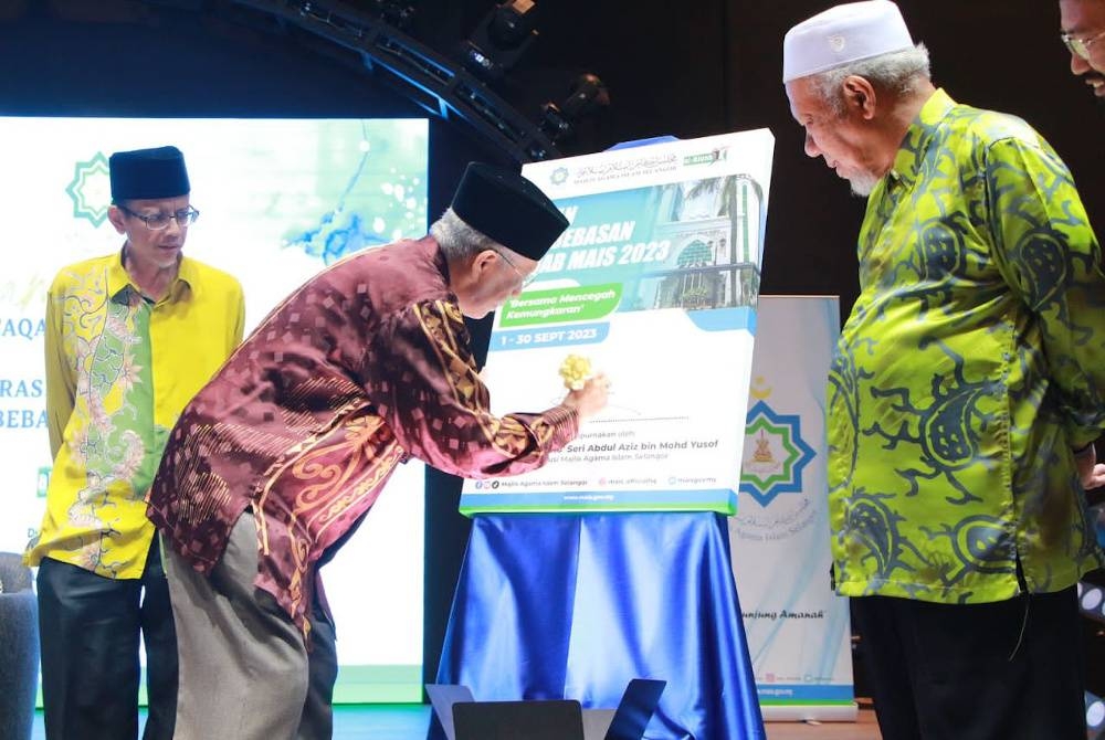 Abdul Aziz sambil diperhatikan oleh Pengerusi Jawatankuasa Riqab MAIS, Datuk Hashim Meon (kanan), dan Setiausaha MAIS, Dr Ahmad Shahir Makhtar menandatangani plak perasmian pada Kempen Bulan Pembebasan Riqab 2023 di sini pada KSL Esplanade Hotel Klang pada Ahad.