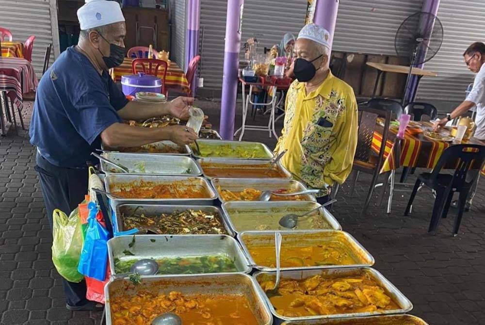 Azahar (kiri) yang menjual makanan melayani pelanggan di kedainya di Gerak Rakyat, Jalan Besar Batu Gajah.