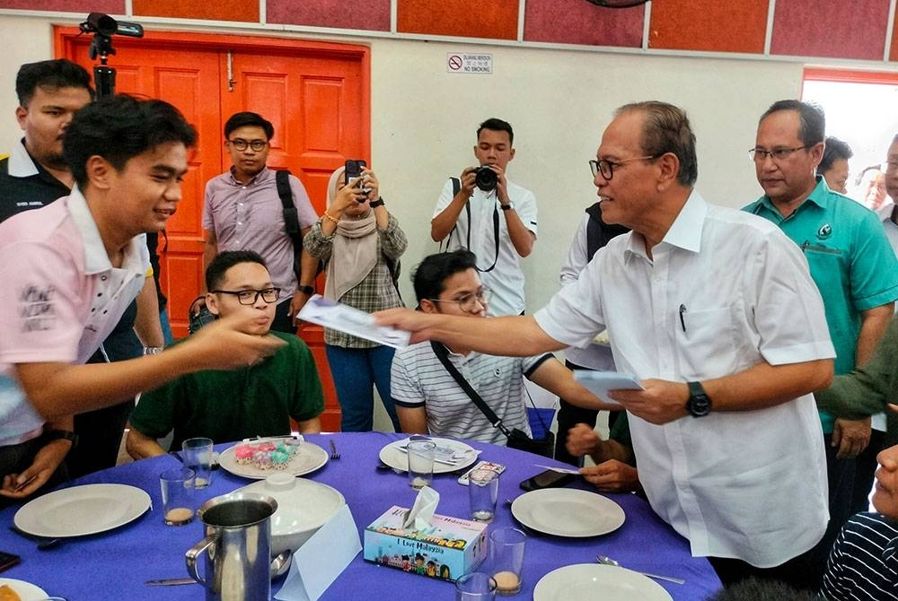 Wan Rosdy (dua dari kanan) ketika menyerahkan Bantuan Prihatin Pahang kepada siswa di DUN Pelangai pada Isnin.