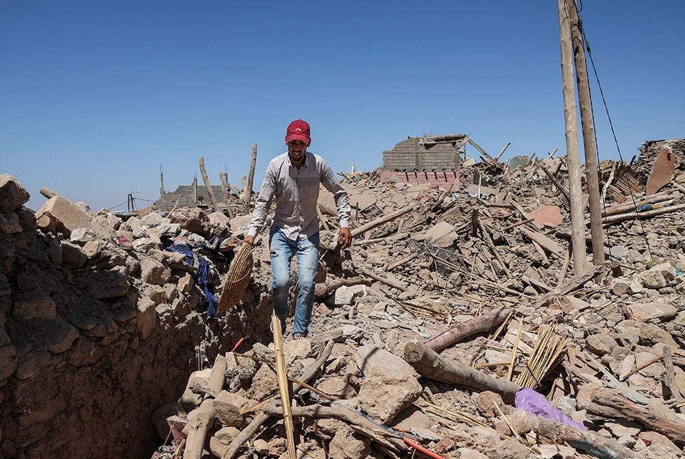 Seorang penduduk cuba dapatkan semula bahan-bahan di bangunan runtuh di perkampungan Tafeghaghte, 60km di selatan Marrakesh, Maghribi pada Isnin. - Foto EPA