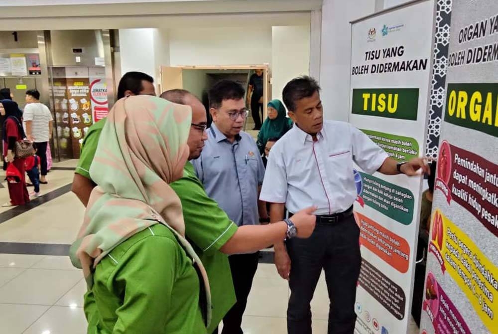 Dr Zaini (kanan) melihat maklumat berkaitan pendermaan organ pada Majlis Perasmian Penutup Minggu Kesedaran Pendermaan Organ Peringkat Negeri Kelantan di HRPZ II pada Selasa.