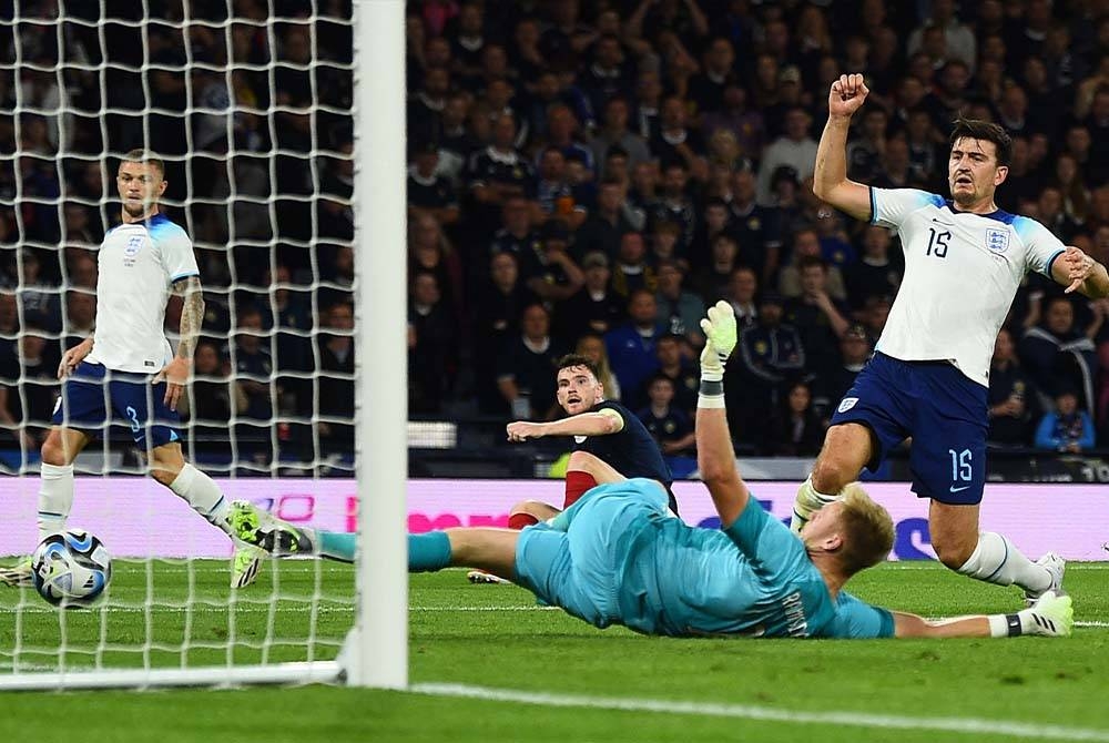 Maguire (kanan) secara tidak sengaja tertampan bola ke dalam gol sendiri dalam aksi persahabatan menentang Scotland. - Foto AFP