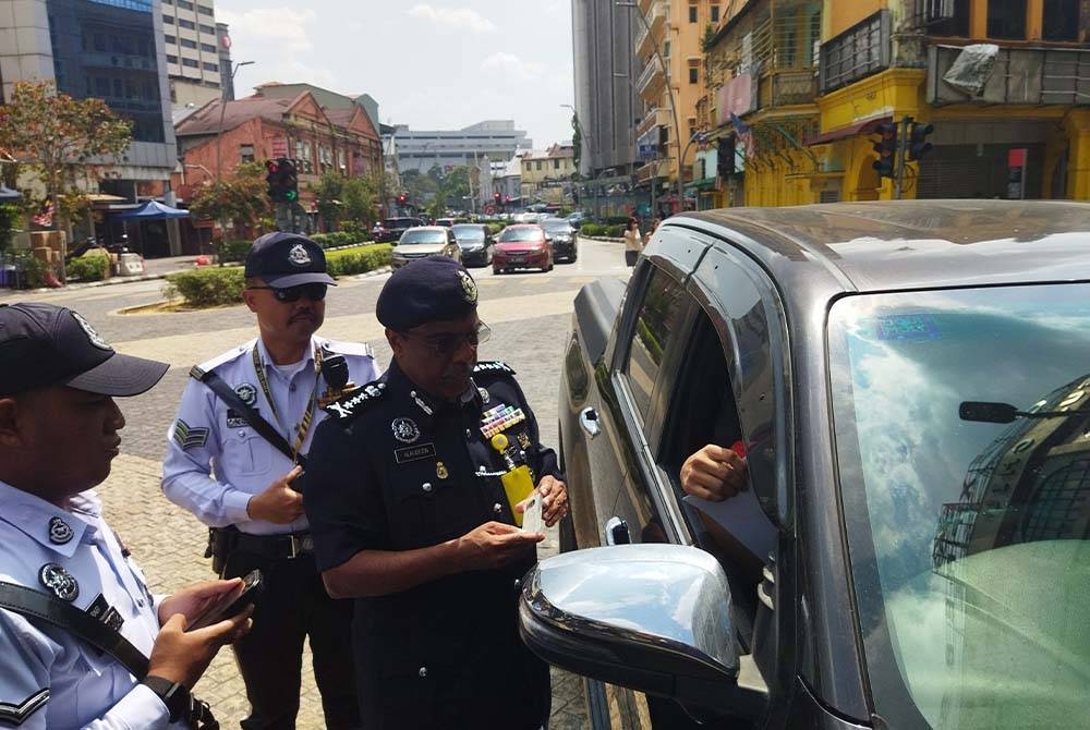 Allaudeen memeriksa pemandu sebuah kenderaan di Jalan Tun Tan Cheng Lock, di sini pada Rabu.