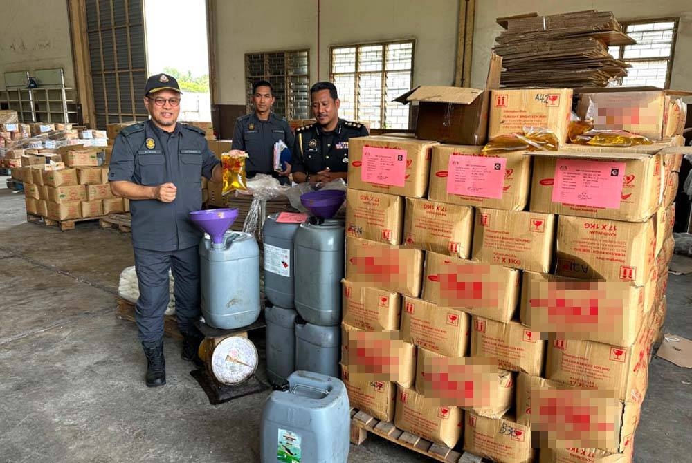 Azman (kiri) memberi contoh minyak masak peket yang akan diisi ke dalam tong berwarna kelabu.