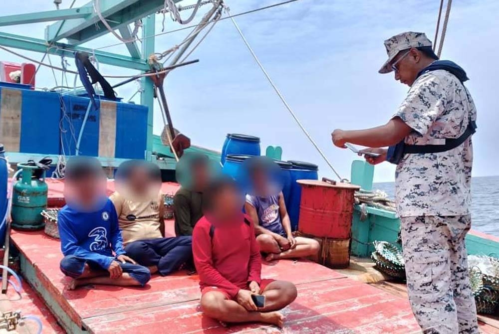 Anggota Maritim Malaysia melakukan pemeriksaan terhadap kru warga asing di atas bot nelayan tempatan yang ditahan di perairan Kuantan pada Selasa.