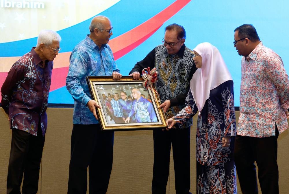 Anwar (tengah) menerima cenderahati daripada Mohammad Redzuan pada Majlis Makan Malam Amal Yayasan Universiti Selangor pada Rabu. - Foto Bernama