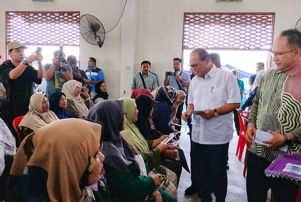 Wan Rosdy (dua dari kanan) menyerahkan BPP kepada penerima dalam majlis tersebut di Dewan Orang Ramai Agropolitan Felda Chemomoi di Bentong pada Khamis.