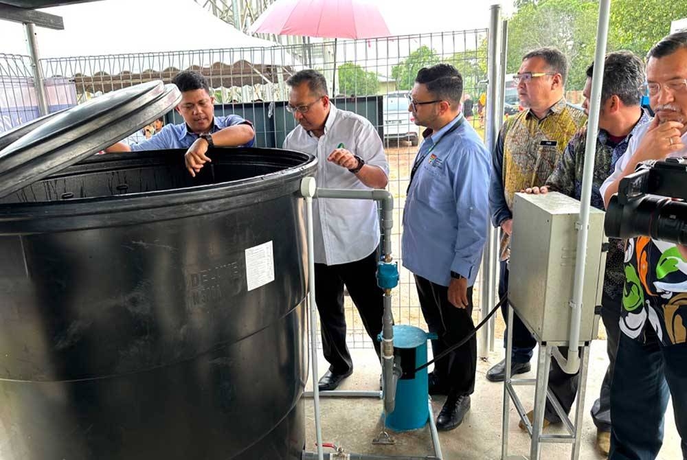 Dr Mohd Hariri (kiri) menunjukkan air yang disimpan ke dalam tangki di kawasan pembinaan telaga tiub.