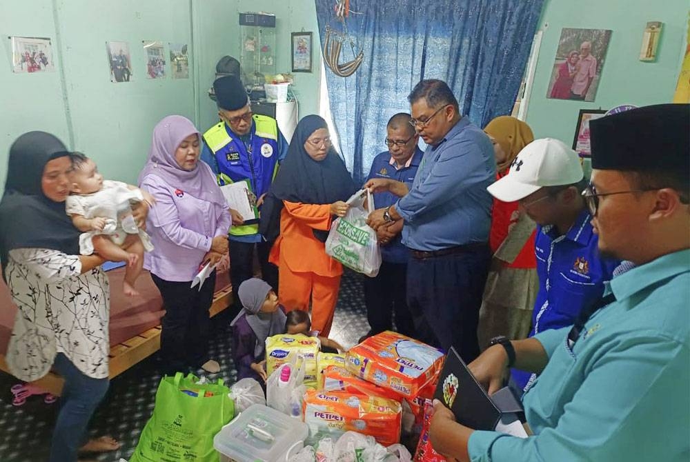 Khairin-Nisa (dua dari kiri) menyaksikan penyerahan bantuan kepada Siti Rahayu daripada pihak Pasar Raya Econsave, Mas Imran di Kampung Seri Bahagia, Plentong, Johor Bahru pada Jumaat.