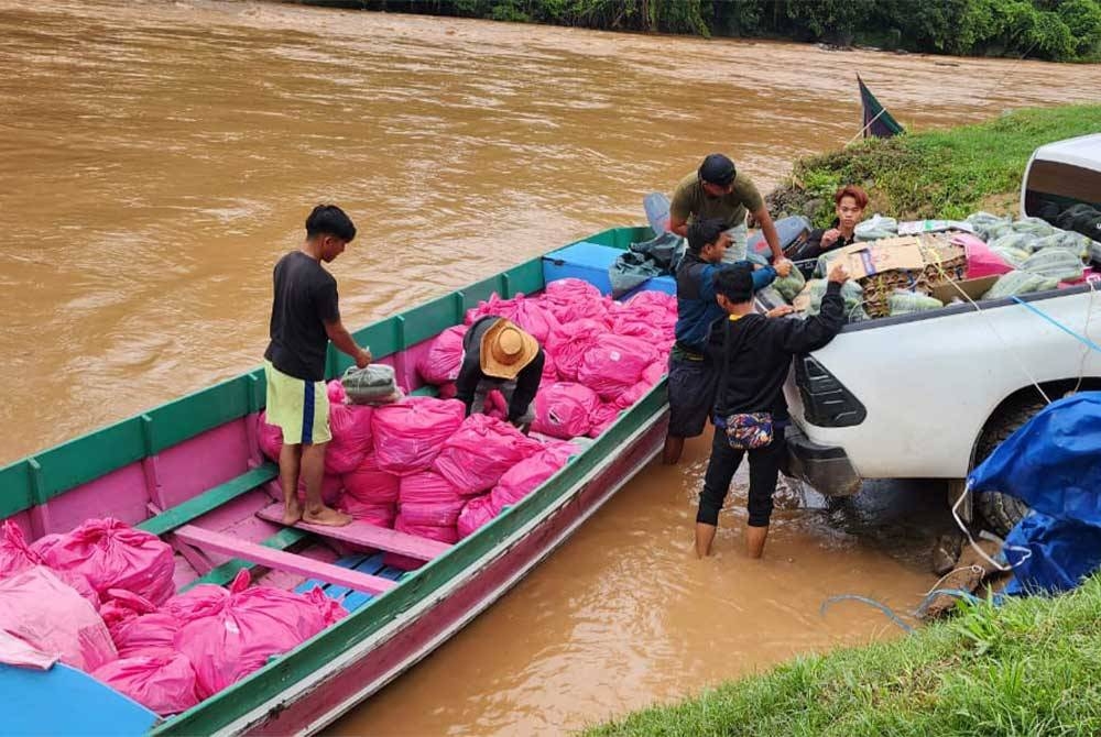 Sukarelawan memunggah bekalan makanan dari bot ke dalam pacuan empat roda di Pensiangan, Sabah.