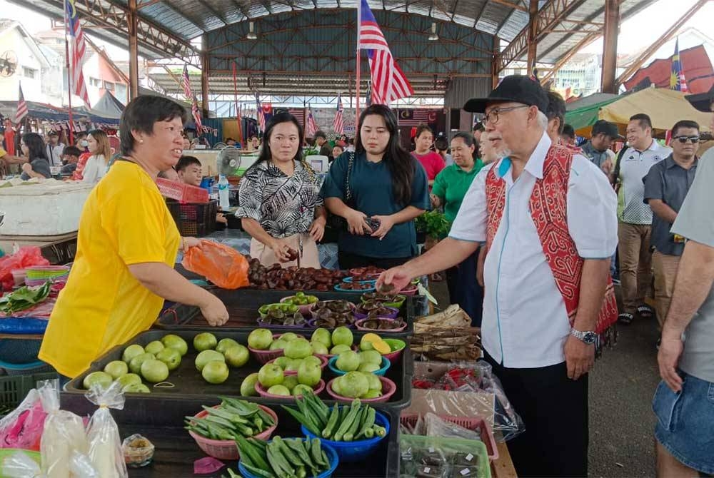 Hassan beramah mesra dengan peniaga selepas Majlis Sambutan Hari Malaysia di Pasar Borneo Johor di Pasir Gudang pada Sabtu.