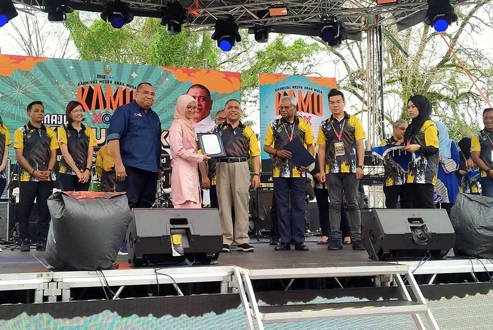 Saarani (hadapan, tiga dari kiri) menyerahkan kontrak pekerjaan kepada belia yang berjaya ketika Majlis Kemuncak Karnival Mesra Anak Muda (KAMU) di Pekarangan Stadium Indera Mulia di sini pada Ahad.