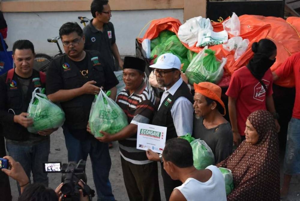 Mas Imran (dua kiri) menyampaikan sumbangan kepada penduduk yang menjadi mangsa gempa bumi di Lombok, Indonesia.