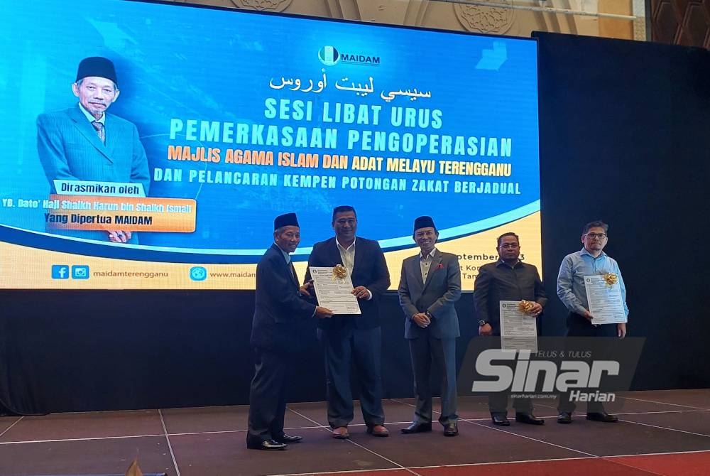 Shaikh Harun (kiri) menyampaikan sijil penyertaan kepada wakil syarikat yang menyertai kempen potongan zakat berjadual anjuran MAIDAM di Kuala Terengganu, pada Selasa.