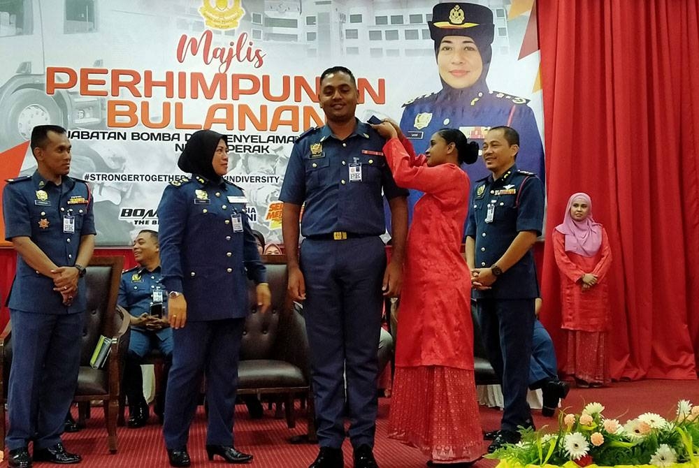 Sayani (dua dari kiri) menyaksikan pemakaian pangkat oleh isteri pegawai bomba ketika Majlis Pemakaian Tanda Pangkat bagi Gred KB24 dan Gred KB22 sempena Majlis Perhimpunan Bulanan JBPM Perak pada Selasa.