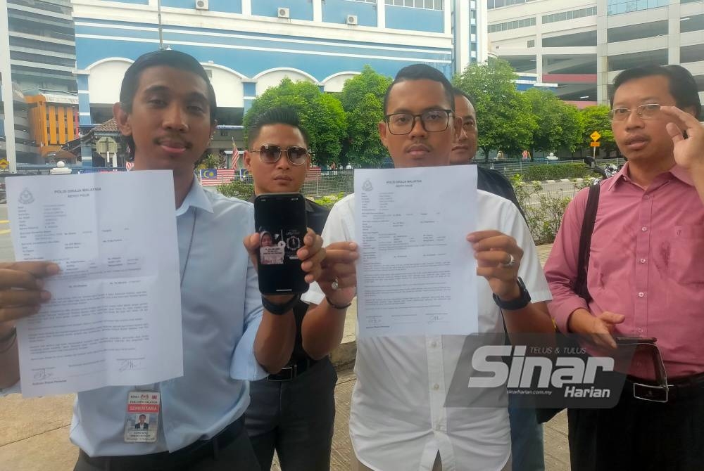 Muhammad Izuan (depan, tengah) bersama ahli AMK menunjukkan laporan polis dan video tular di media sosial menghina Perdana Menteri di hadapan IPD Dang Wangi, Kuala Lumpur pada Selasa.