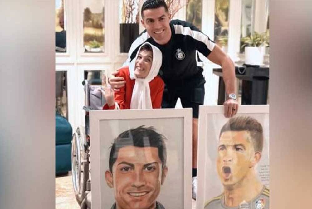 Fatemeh menyerahkan dua potret lukisannya kepada Ronaldo yang dihasilkan menggunakan kakinya. - Foto Twitter/FAISAL RSL