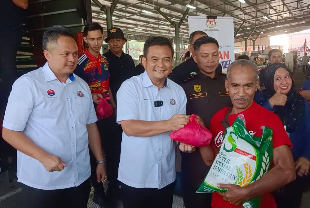 Zahar menyerahkan beras kepada seorang penerima ketika Program Jualan Agro Madani di Pasar Tani Kekal, Jalan Datin Halimah, Johor Bahru pada Rabu.