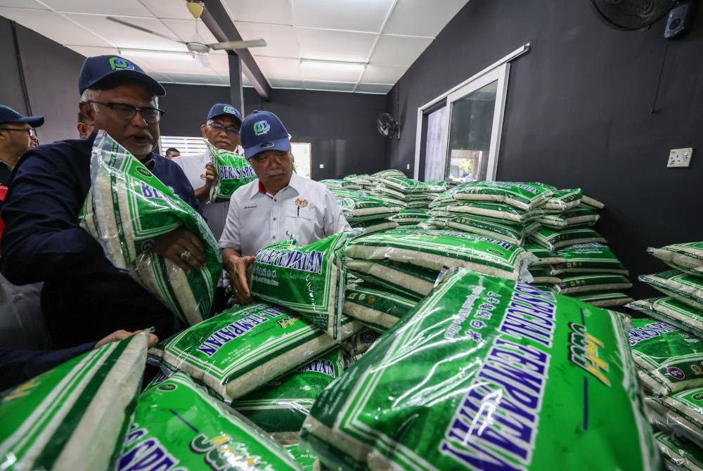 Mohamad Sabu (kanan) melihat beras tempatan yang akan dijual kepada orang ramai menerusi Program Jualan Agro Madani pada Rabu. - Foto Bernama