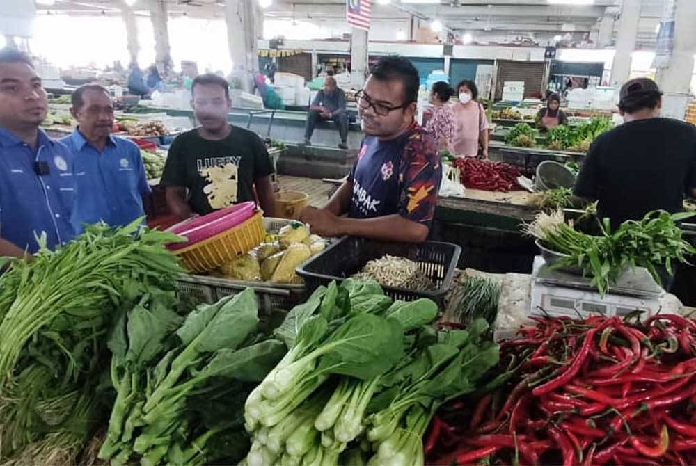 Mohamad Yusrizal (kiri) semasa membuat tinjauan harga sayuran di Pasar Besar Alor Setar pada Rabu.