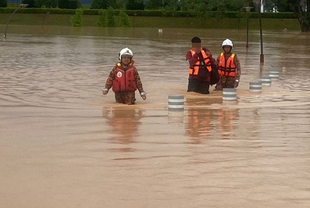 Bomba mengiringi seorang lelaki terperangkap di kawasan pondok berdekatan tasik akibat limpahan air di Taman Serinia TY Park, Dengkil pada Rabu.