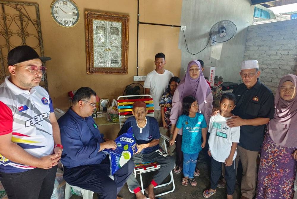 Mas Imran (kiri) menyampaikan bantuan barang dapur sumbangan Pasar Raya Econsave kepada Marzuki di rumahnya di Permas Jaya, Johor Bahru pada Rabu.