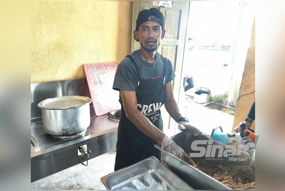 Mohd Radzi membungkus perapan daging kambing yang telah ditempah pelanggannya di Pantai Sungai Kajang, Tanjong Karang pada Selasa.