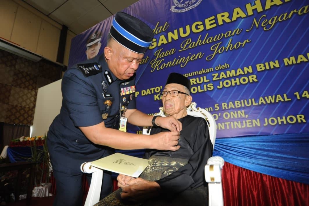 Kamarul Zaman menyematkan pingat kepada bekas anggota polis, Awang Daud sempena Istiadat Penganugerahan Pingat Jasa Pahlawan Negara Kontinjen Johor di IPK Johor pada Khamis. 