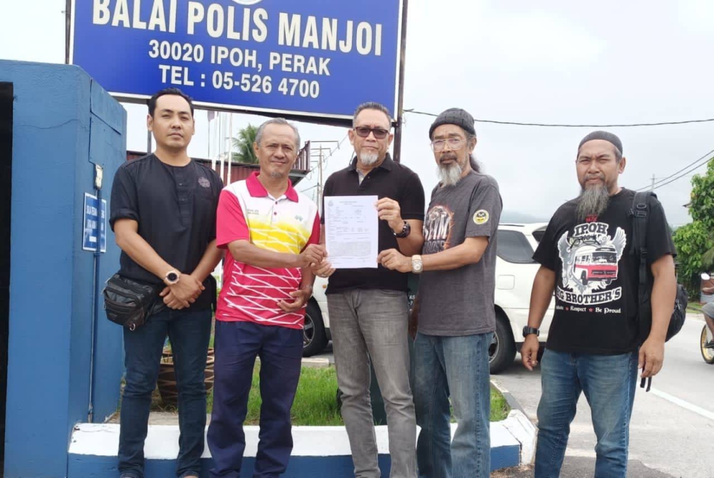 Amiruddin (tengah) menunjukkan laporan polis yang dibuat oleh Jabat Perak terhadap Howard Lee di Balai Polis Manjoi pada Khamis.