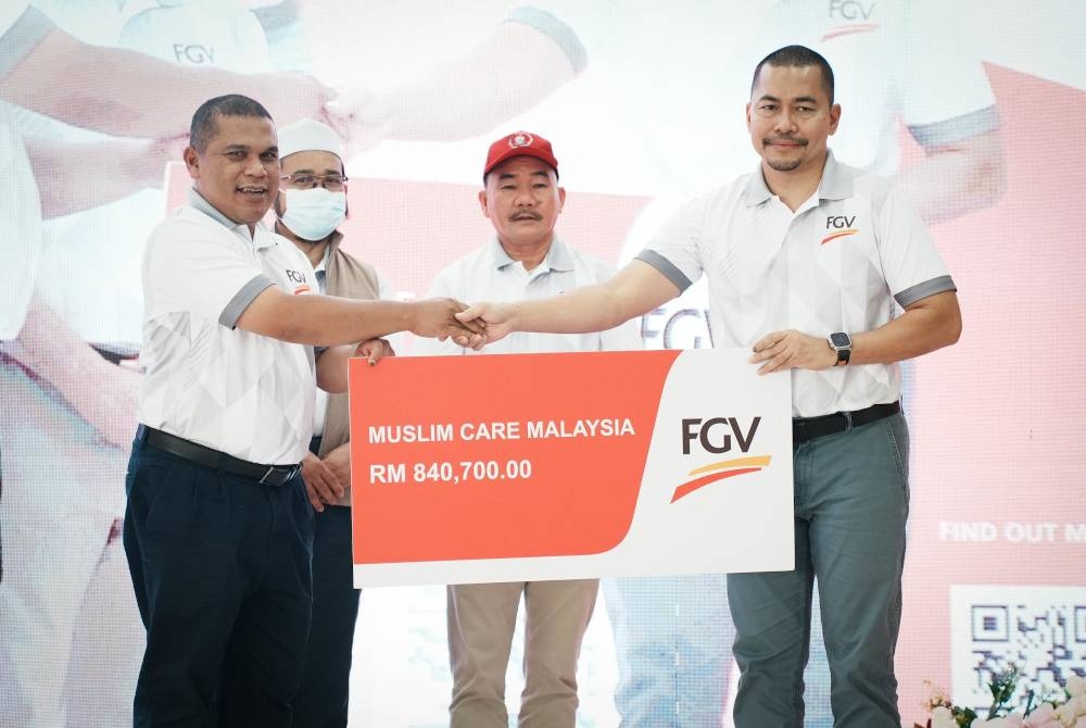 Nazrul (kanan) menyerahkan replika cek tajaan program FGV Seikhlas Hati sebanyak RM840,700 kepada Haji Zulkifli Wahijan sambil diperhatikan Ruslan (dua dari kanan) dan Bungsu.