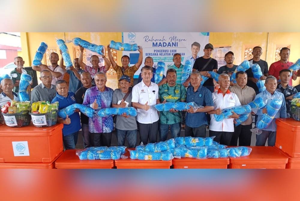 Muhammad Faiz (tengah) bersama nelayan yang menerima bantuan alatan menangkap ikan sempena program Rahmah Mesra Madani di Kompleks Perikanan LKIM Kuala Kemaman pada Jumaat.