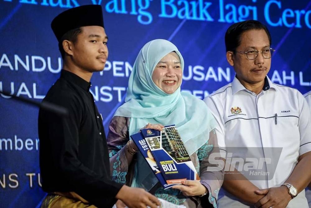 Fadhlina menerima buku Garis Panduan Pengurusan Buli dan Gangguan Seksual selepas melancarkannya di Sekolah Menengah Sains Tun Syed Sheh Shahabudin pada Jumaat.