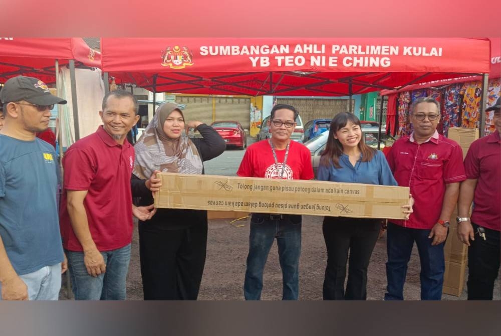 Nie Ching (dua kanan) menyerahkan khemah kepada wakil Persatuan Peniaga dan Penjaja Daerah Kulai di Pasar Pagi Merbau, Bandar Putra, Kulai pada Sabtu