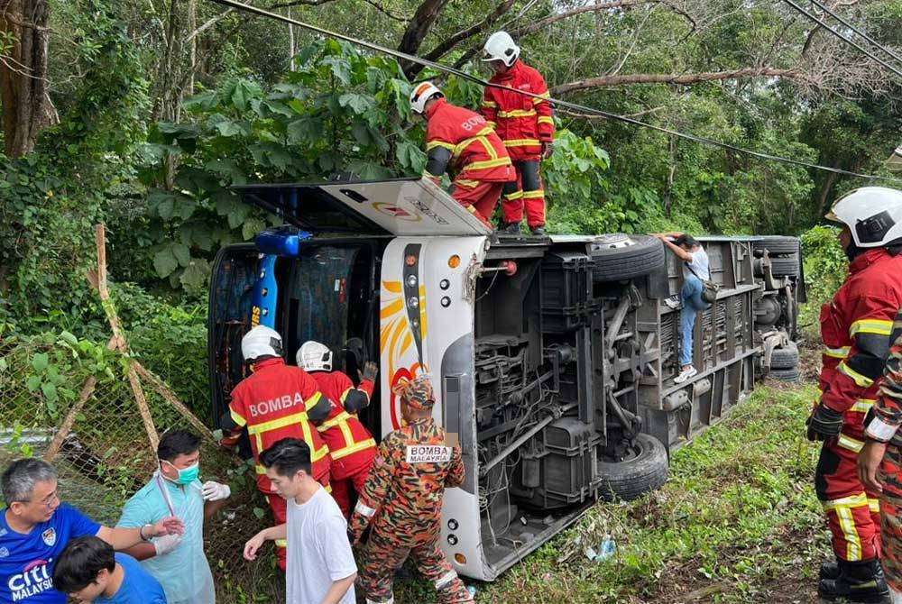 Anggota bomba membantu mengeluarkan mangsa dari sebuah bas persiaran yang terbabas dan terbalik dalam kemalangan di Kampung Baru Si Rusa, Port Dickson, pagi Sabtu.