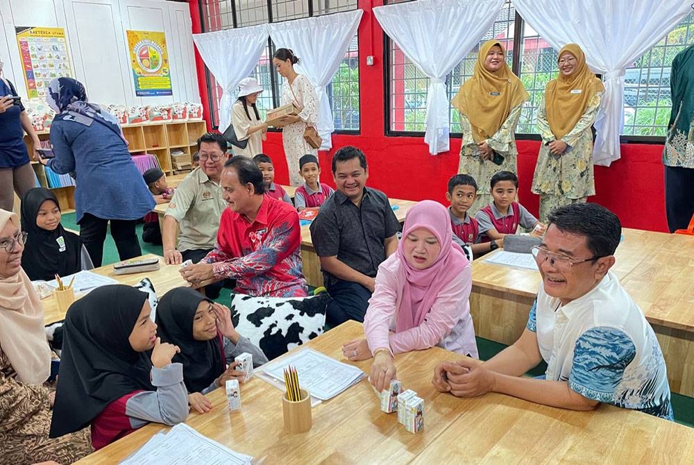 Fadhlina (duduk dua dari kanan) bermesra dengan beberapa murid ketika merasmikan Pusat Pencegahan Kemiskinan Multidimensi di SK Sungai Acheh pada Ahad.