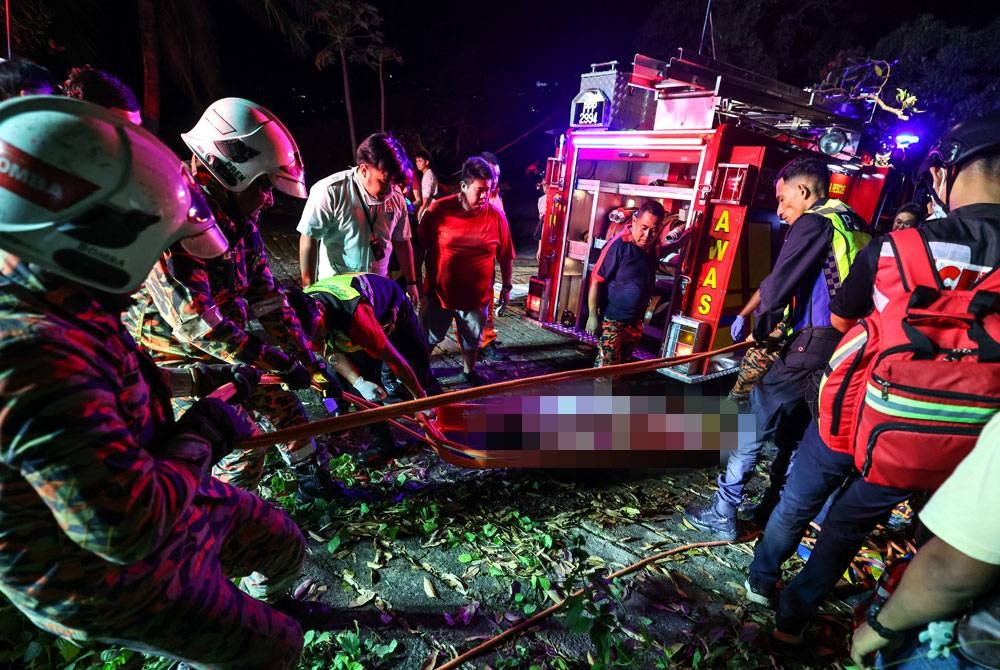 Anggota JBPM Pulau Pinang berjaya mengeluarkan salah seorang mangsa dari dalam van yang terbabas ke dalam cerun di Bukit Genting malam ini. - Foto Bernama