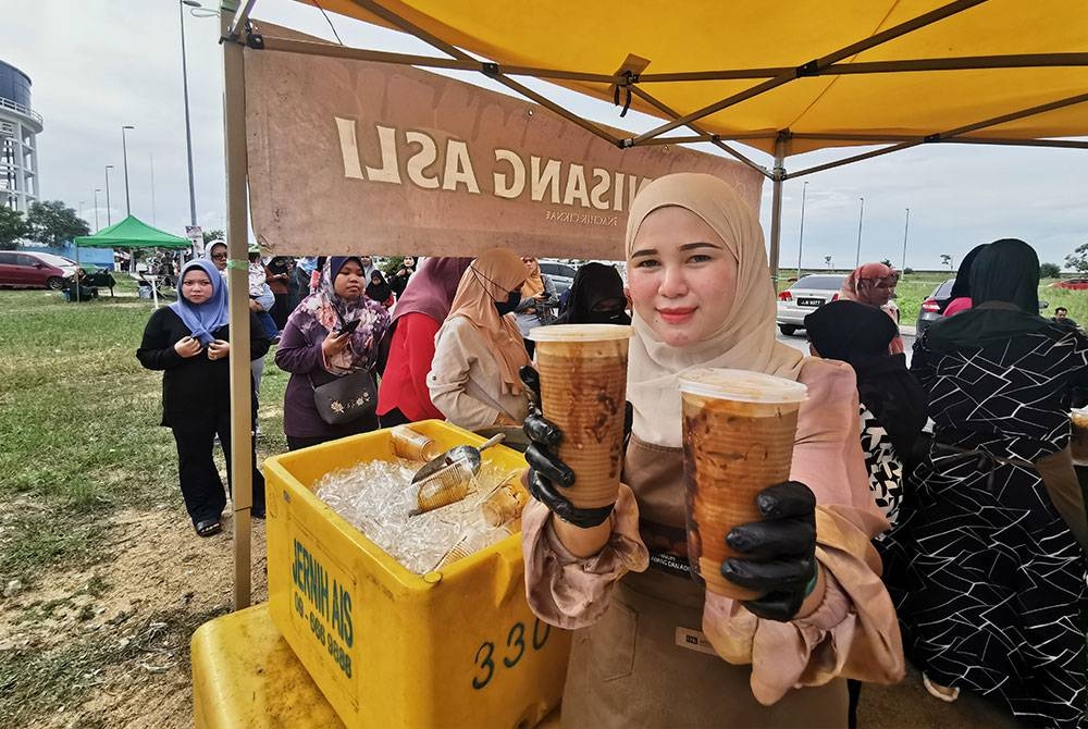 Nur Nadirah Syuhadah menunjukkan kopi nisang asli yang diagihkan kepada orang ramai gerai Kopi Nisang Asli di jambatan angkat, Kuala Terengganu.