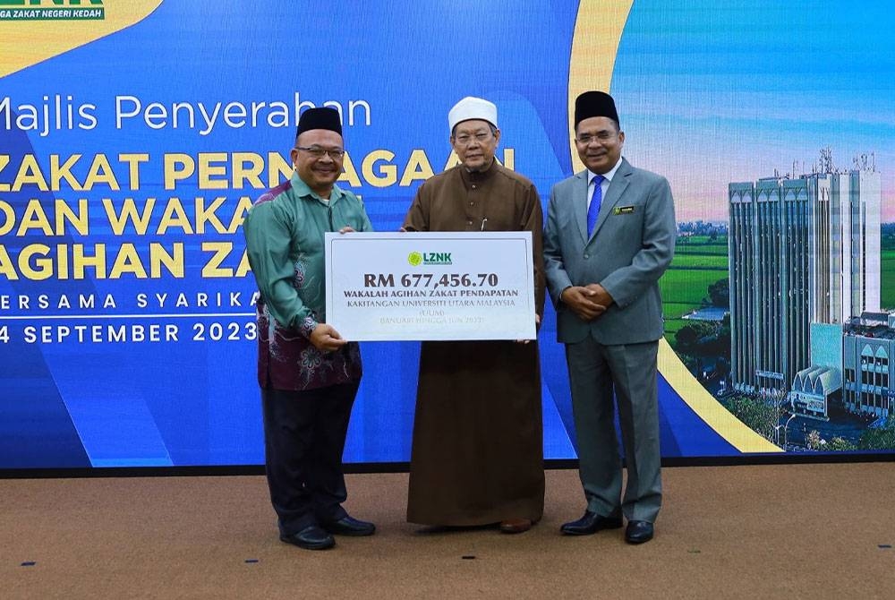 Fadzil ( tengah) menyempurnakan penyerahan wakalah agihan zakat kepada Mohd Foad (kiri) disaksikan Zakaria (kanan).