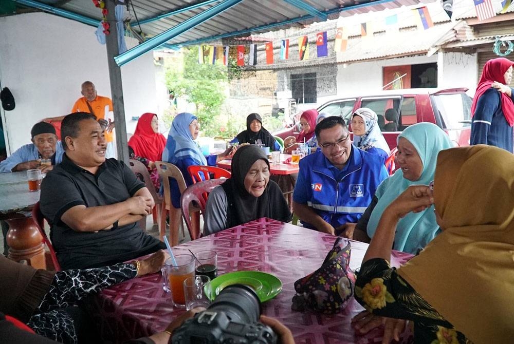 Amizar (tengah) bersarapan pagi dan beramah mesra bersama penduduk di Felda Chemomoi pada Isnin