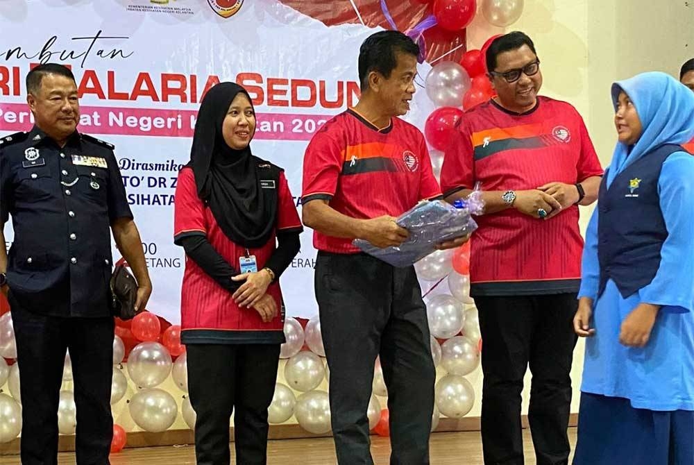 Dr Zaini (tiga darikiri) menyampaikan hadiah kepada penerima pada Program Sambutan Hari Malaria Sedunia Peringkat Kelantan di dewan serbaguna Ladang Sungai Terah, Gua Musang.