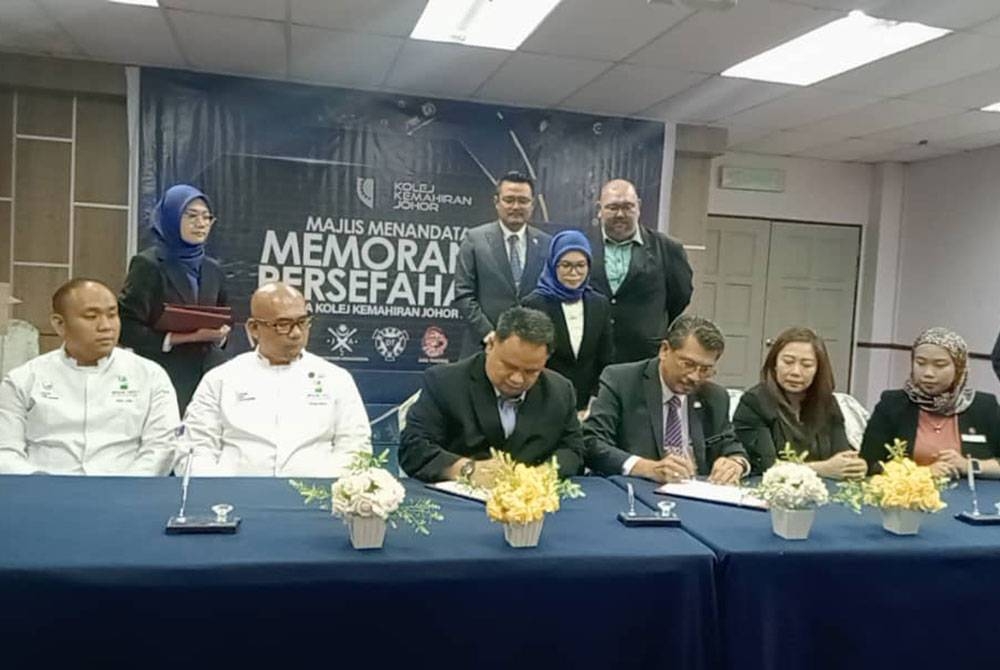 Mohd Hairi (berdiri, tengah) menyaksikan MOU Kolej Kemahiran Johor dengan empat rakan strategik dalam bidang pembuatan dan penyediaan makanan serta automotif di Hotel Seri Malaysia, Larkin, Johor Bahru pada Isnin