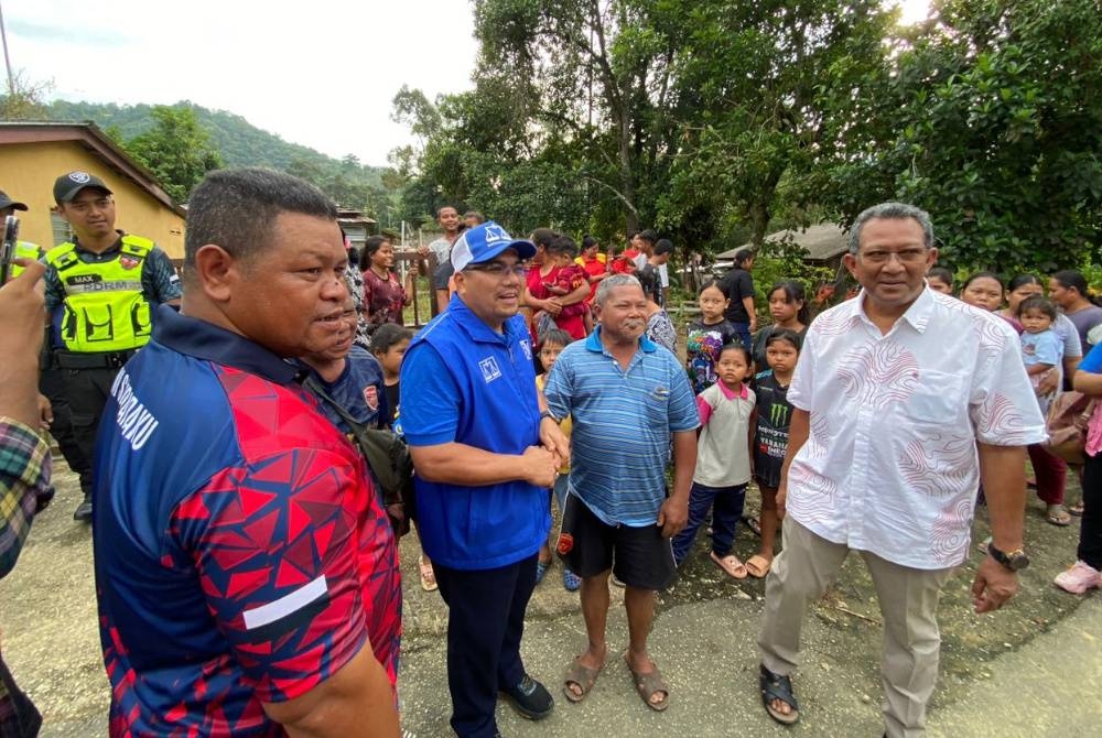 Amizar (dua dari kiri) menyantuni penduduk Kampung Orang Asli Sungai Gapoi.