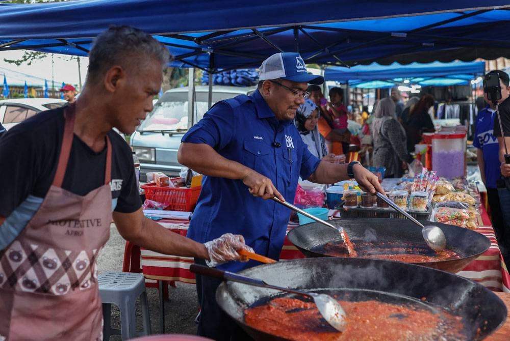 Amizar beramah mesra bersama peniaga sempena kempen PRK DUN Pelangai di tapak pasar malam Felda Chemomoi pada Ahad. - Foto Bernama