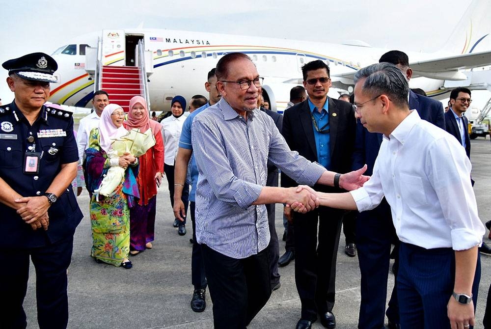 Anwar (tengah) dan Wan Azizah disambut oleh Fahmi (kanan) sejurus tiba di Kompleks Bunga Raya KLIA hari ini. - Foto Bernama