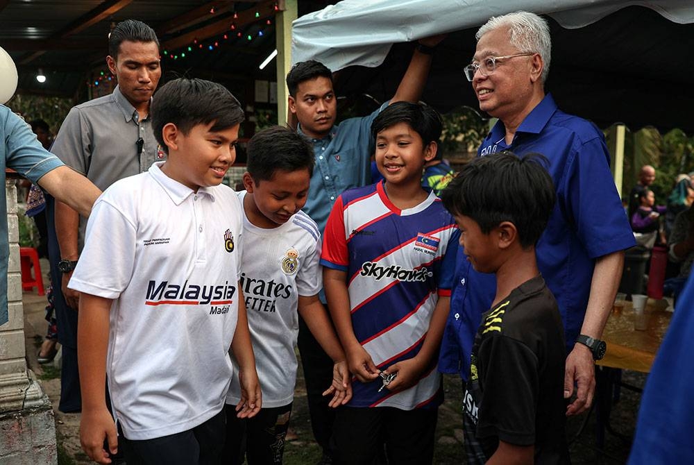 Ismail Sabri (kanan) menyantuni anak muda Felda Kampung Sungai Kemahal sempena kempen PRK DUN Pelangai hari ini. - Foto Bernama