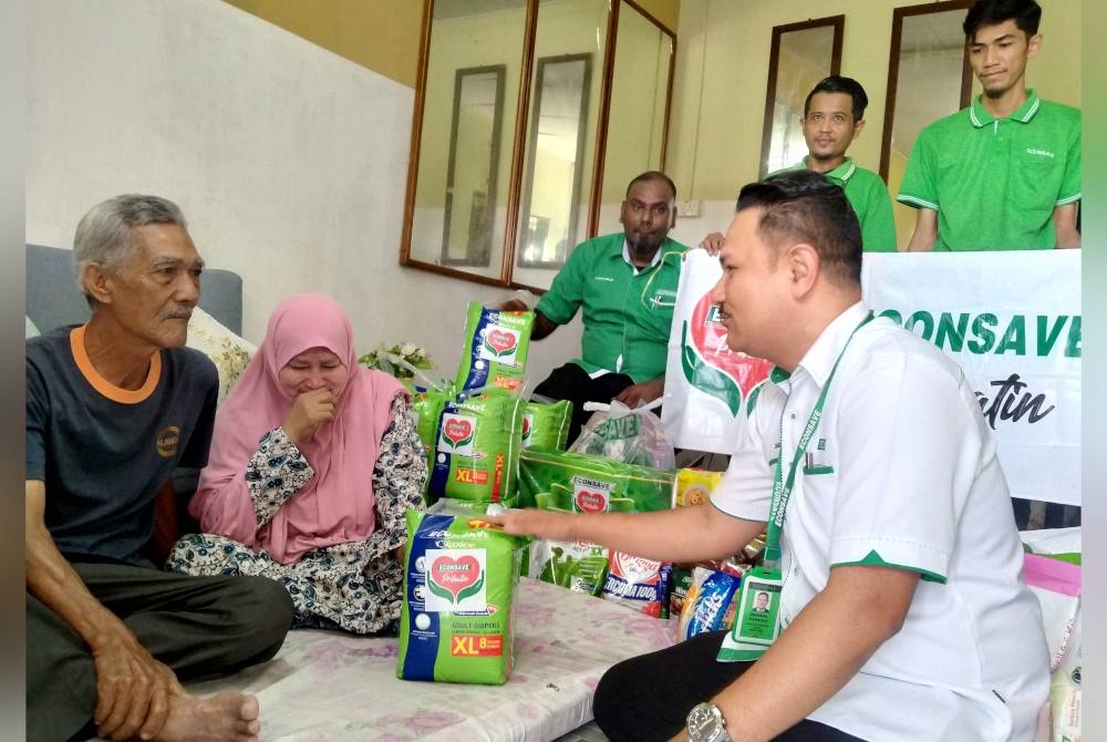 Santariyah (dua dari kiri) sebak ketika dikunjungi Zamzuri (kanan) dan kakitangan Econsave yang menyampaikan sumbangan barang keperluan bernilai RM1,000.