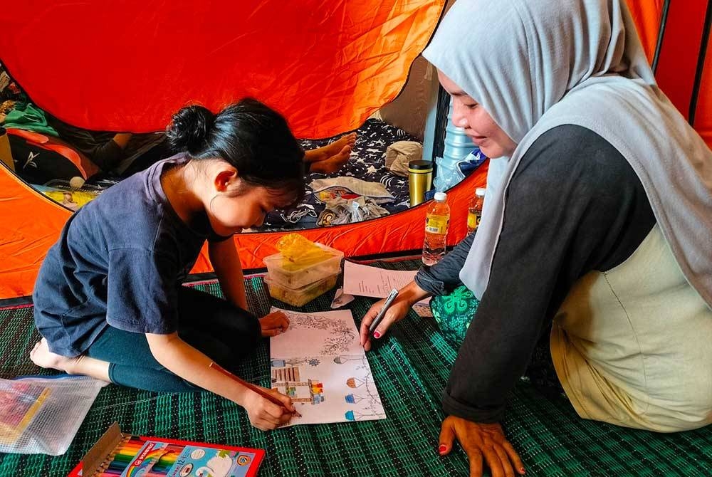 Syuhaida melihat anaknya, Aryiffa Airis Muhammad Patrick Idham, 8, mewarna di PPS SK Bukit Hijau pada Khamis.