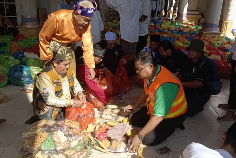 Mas Imran (kanan) dan Hashim (berdiri, kiri) membantu menyediakan makanan ringan dan tradisional dalam majlis Peringatan Maulid Nabi Besar Muhammad SAW di Masjid Besar Jam&#039;yiyatul Qudsiyyah Kecamatan di Pringgasela, Lombok Timur, Lombok Timor, Indonesia pada Khamis.