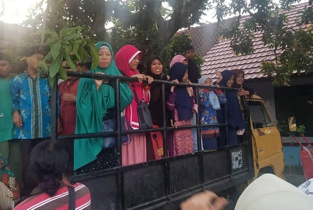 Pelajar buta Sekolah Yayasan Dewasa Pelita Harapan di Mataram, Lombok Timur, Lombok Timor, Indonesia menaiki lori disewa